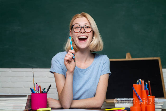 有趣的女青年教师在教室里.年轻的老师戴着眼镜,背景是绿色的黑板.