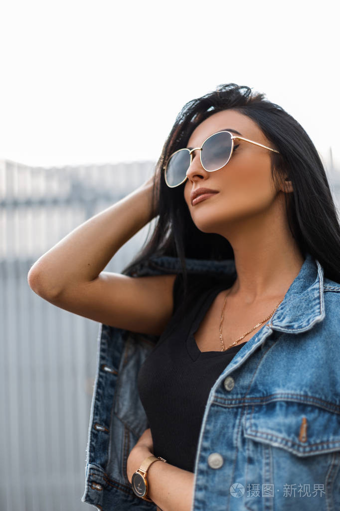 美丽的年轻时髦女子戴着时尚的墨镜,穿着时髦的黑色t恤,穿着时髦的