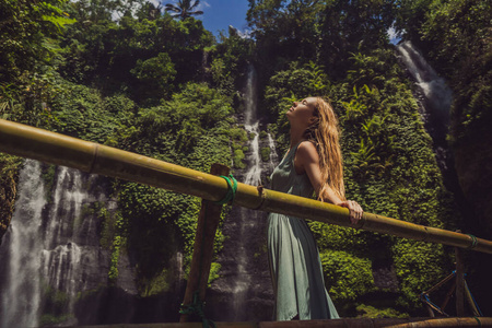 印尼巴厘岛丛林中的塞库姆普尔瀑布,一位穿着绿松石衣服的妇女.