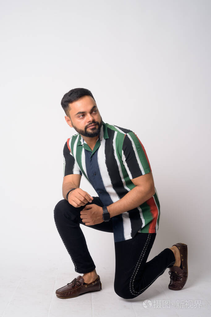 一个留着胡子的年轻印度男子蹲下思考的全身照片