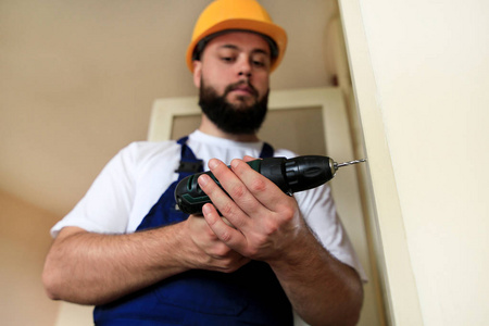 在工地上,建筑工人用电钻在木墙门上钻了个钉子孔.家居装修概念.