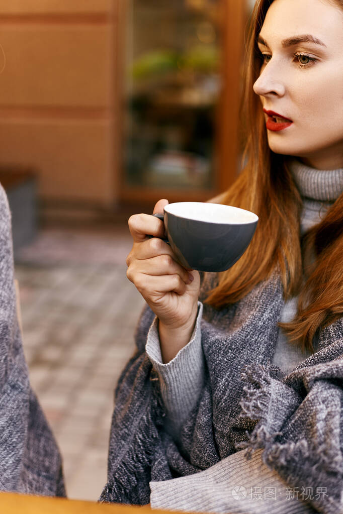 穿格子花呢的女孩端着一杯咖啡