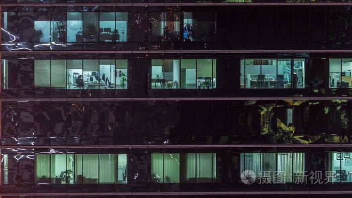 办公室摩天大楼的外部在深夜室内灯亮着人们在夜间时间点内工作