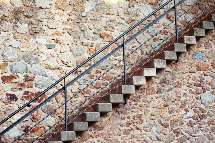 斜向沿着旧石墙有铁栏杆的楼梯
