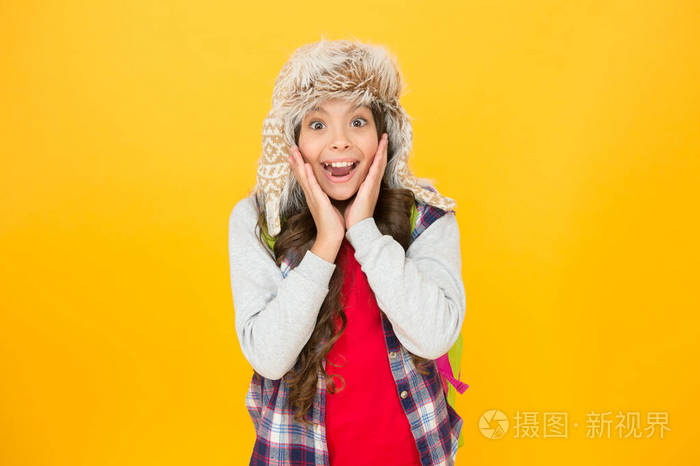 穿着时尚冬装的惊喜女孩.小孩子戴着毛皮帽子,表情很惊讶.