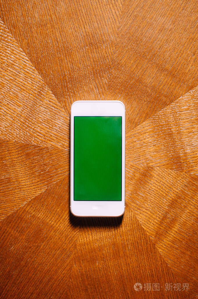 桌上放着一台绿色屏幕的平板智能手机