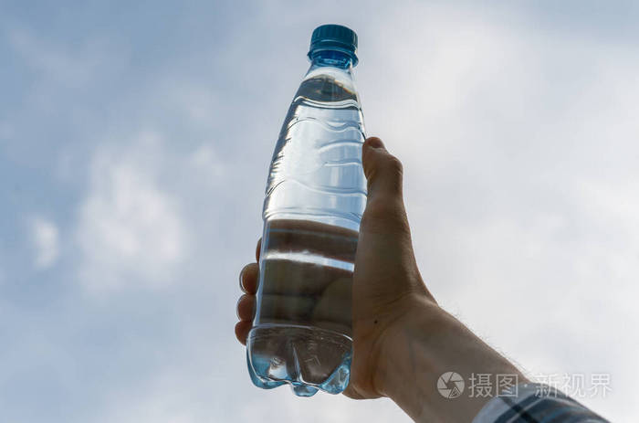 手拿着一个装着纯净水的塑料瓶对着天空