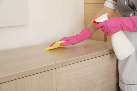 年轻的女服务员在酒店房间用抹布擦灰尘,特写.文本空间照片