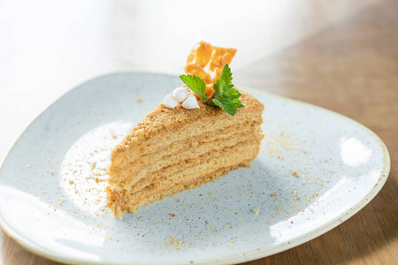 早上卡布奇诺咖啡和糕点用蛋白酥皮和薄荷叶装饰的蜂蜜海绵蛋糕.