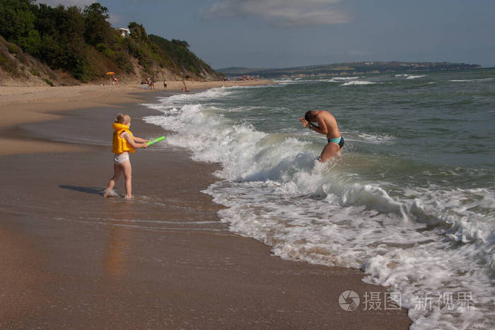 两个孩子一个男孩和一个女孩，一个哥哥和一个妹妹正在海边的水里玩耍。