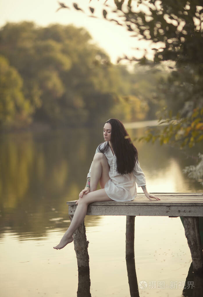 一位年轻女子坐在河边的桥上湖边的仙女女孩