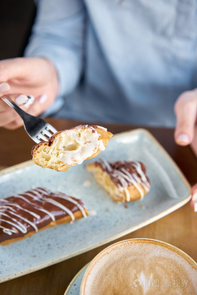 一位年轻女子在餐馆喝咖啡卡布奇诺,吃甜点.传统法式巧克力蛋糕.