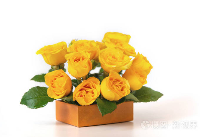 一束黄玫瑰放在一个白色背景的橙色小盒子里。花是水平特写