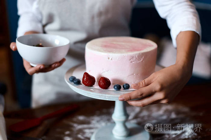 厨师端着一碗浆果做生日蛋糕