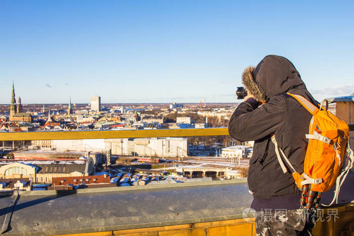 摄影师拎着大包从高处拍摄欧洲古城的地标。拉脱维亚科学院。冬日晴朗。里加，欧洲，波罗的海，拉脱维亚。旅游照片概念