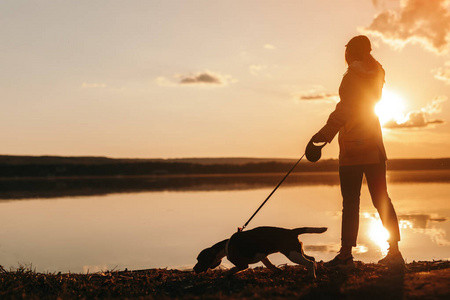 不认识的女人牵着狗在池塘边散步照片