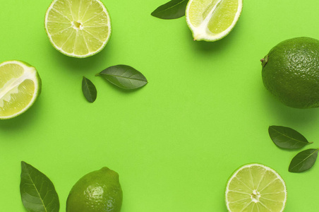 新鲜多汁的青柠和绿叶,背景为鲜绿色.俯视图平面复制空间.