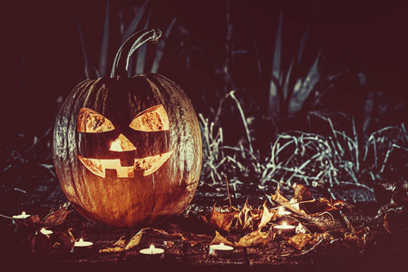 万圣节南瓜头杰克灯与蜡烛周围的旧板在一个诡异的夜晚景观.软聚焦.