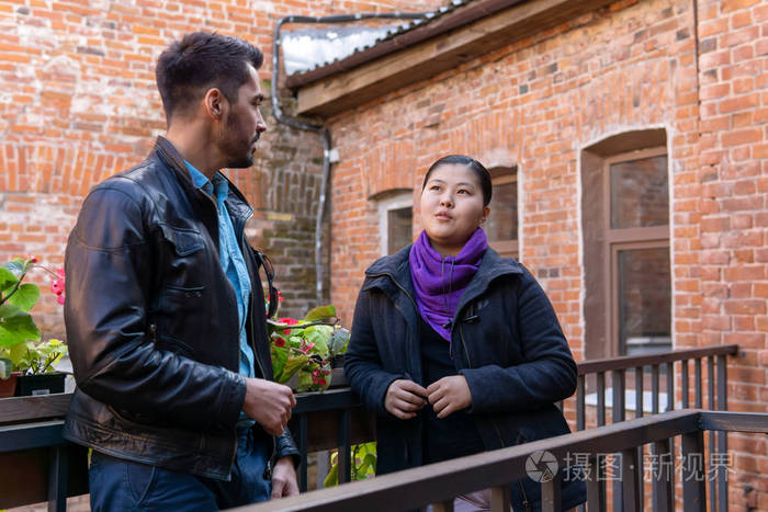 年轻男女站在阳台上聊天