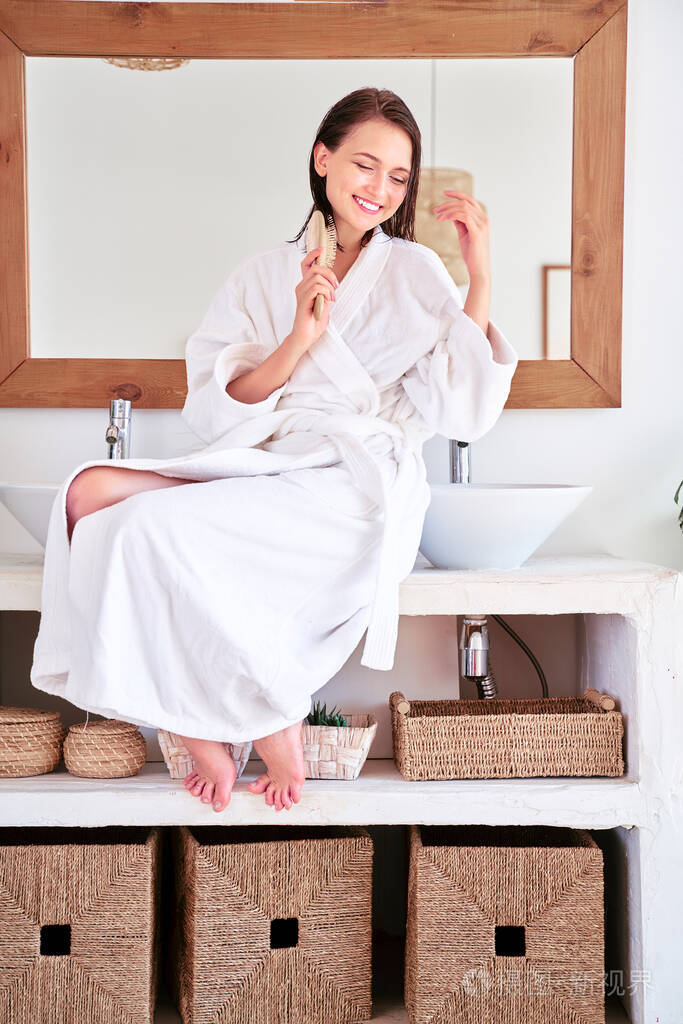 一位梳着梳子头发湿漉漉的年轻女子坐在浴缸里