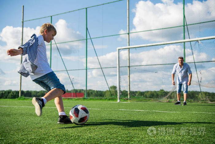 父亲和儿子在草地上踢足球的低处
