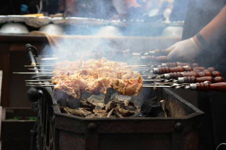 一个戴白手套的男人的手,在城市街道咖啡馆的烤架上烧烤照片