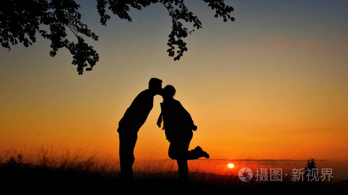 一对情侣在夕阳下亲吻的剪影