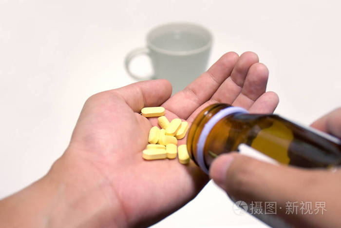 药丸在手有杯子和药瓶一只手从瓶子里往另一只手里倒药片