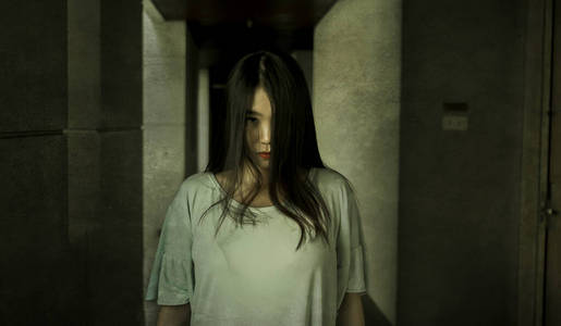 日本恐怖电影风格的年轻奇怪的亚洲女孩晚上在黑暗孤独的酒店走廊里