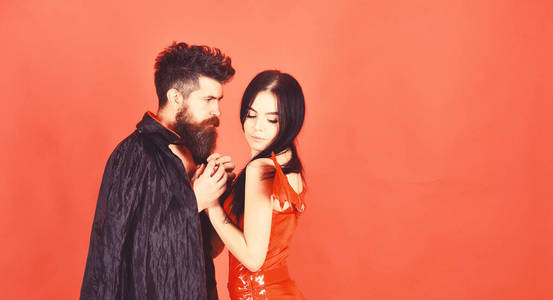 男人和女人打扮得像吸血鬼,恶魔,红色背景.披着斗篷的吸血照片