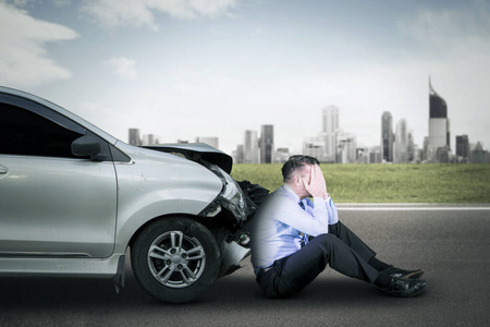 伤心的商人在开玩笑伤心的商人在路上一辆损坏的汽车附近照片