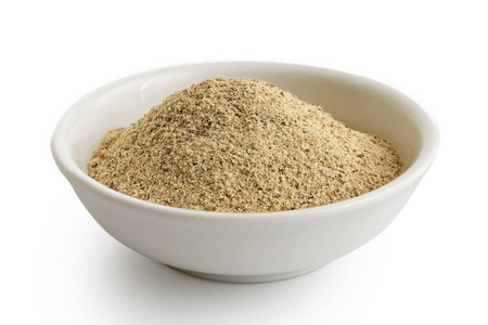 细碎的白胡椒粉放在白色陶瓷碗里照片