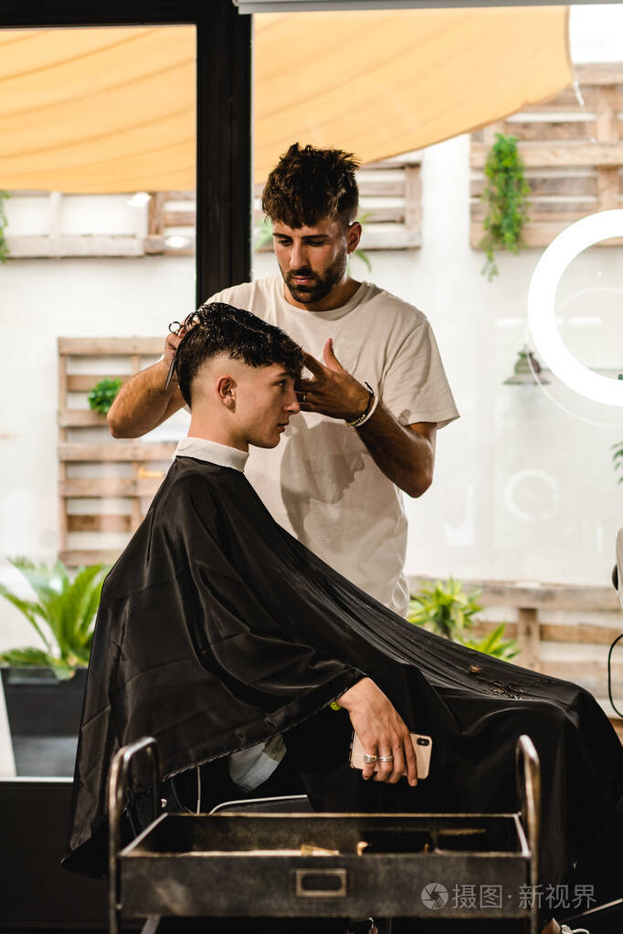 男士发廊理发师在理发店理发年轻的男客户和美发师