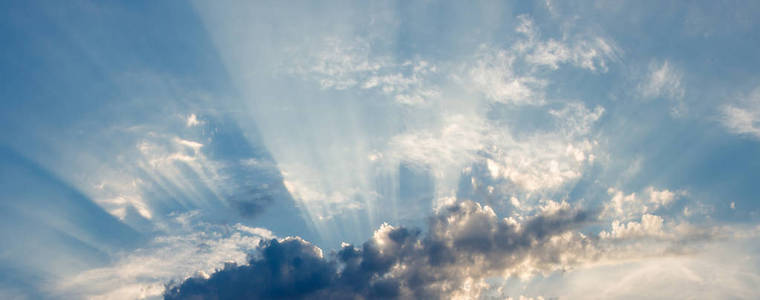 在蓝天和雷雨的背景下,太阳光直线穿过云层照片