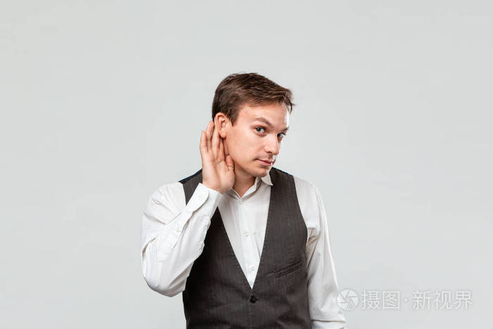 Handsome young man in a white shirt and grey vest holding hand c