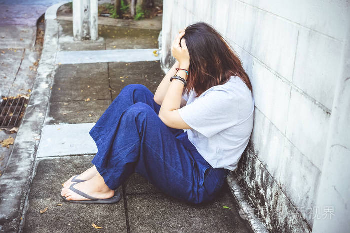 年轻的亚洲女孩坐在压力和情绪低落