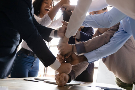 喜出望外的多民族商业团队把拳头叠在一起,特写照片