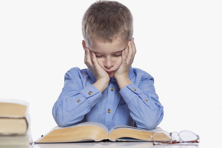 疲劳学习一个小学生正在桌边做作业.学习带来的悲伤和疲劳.