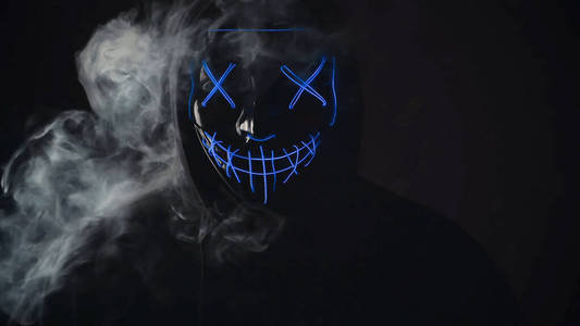 男人愤怒和可怕的灯光霓虹灯夜光面具在黑色背景烟雾罩.