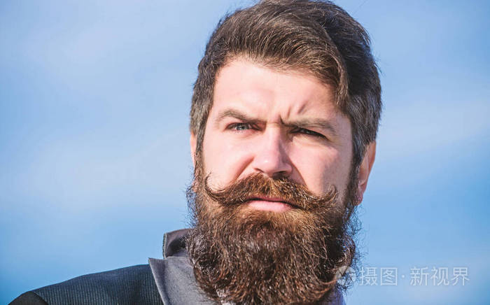 投资时尚的外观胡子长得很快男人胡子时髦的穿着正式西装蓝天背景面部