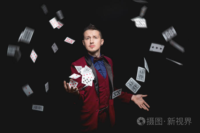 魔术师在黑色背景上用扑克牌展示魔术