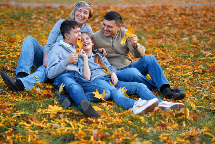 快乐的一家人在秋天的城市公园度假孩子们和父母摆姿势微笑玩耍玩得