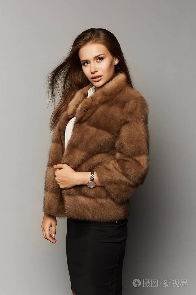 美丽的女士优雅的发型穿着奢华的皮草大衣背景是孤立的时尚人造毛皮穿