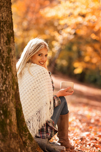 美丽的女孩在秋天休息和喝咖啡图片