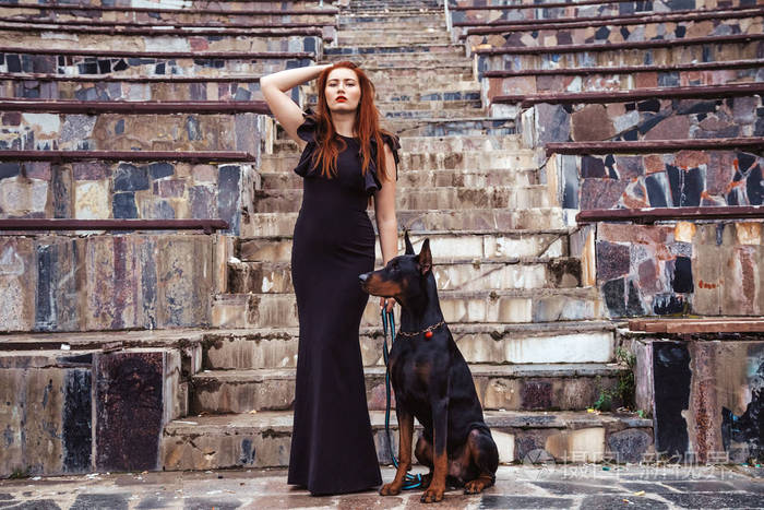 美女主人和她的狗黑色杜宾一起在户外散步