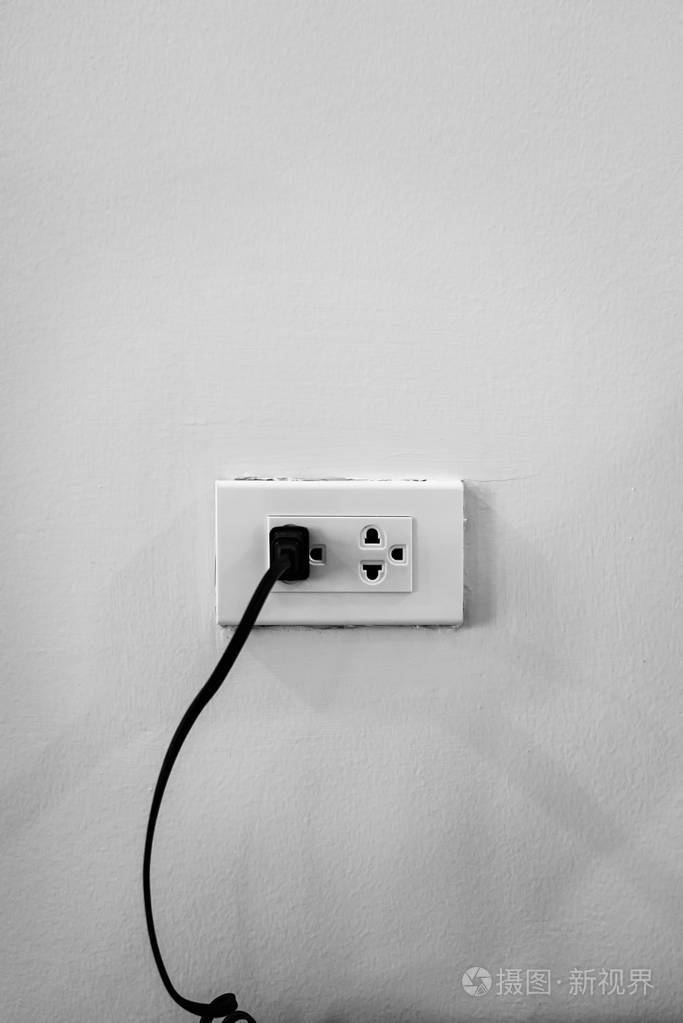 白色墙上连接黑色电线的电源插座