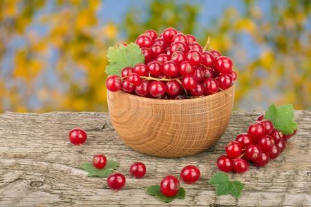 红色的小葡萄干浆果采用木制的碗向木制的表和模糊的英语字母表的第7个字母