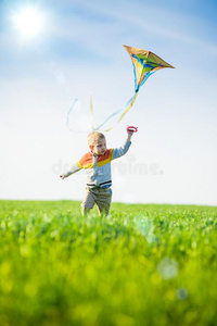 年幼的男孩演奏和他的风筝采用一绿色的田.