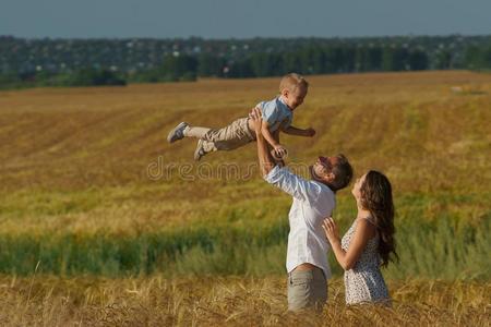 年幼的双亲和小孩步行通过小麦田