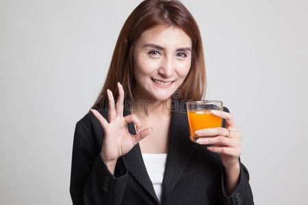 年幼的亚洲人女人喝桔子果汁给看ohnekosten不计价符号.